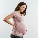 Pregnant woman demonstrating pregnancy back pain relief without medication through gentle stretching exercises